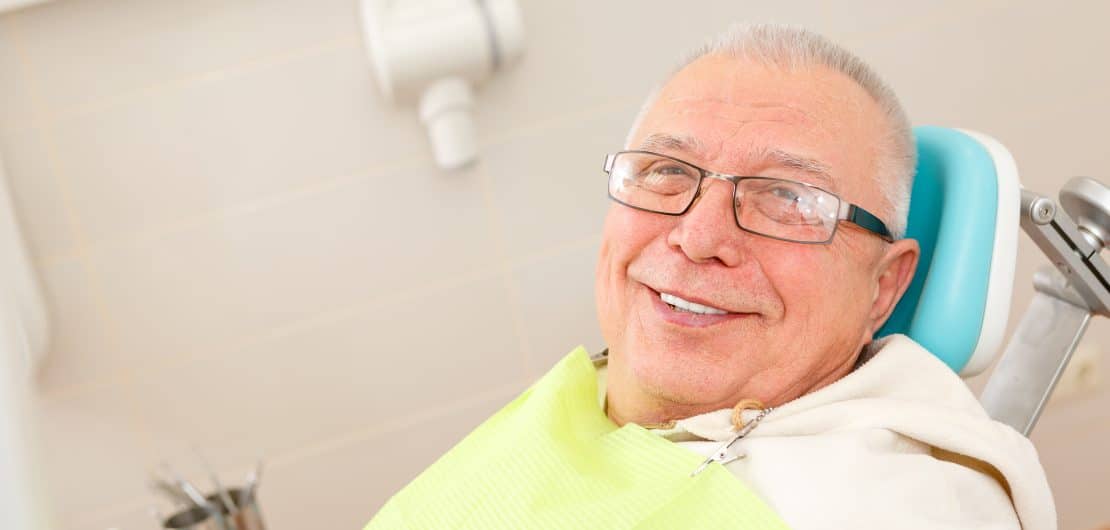Smiling older man wearing glasses in dental chair at Brookings Dental Arts office